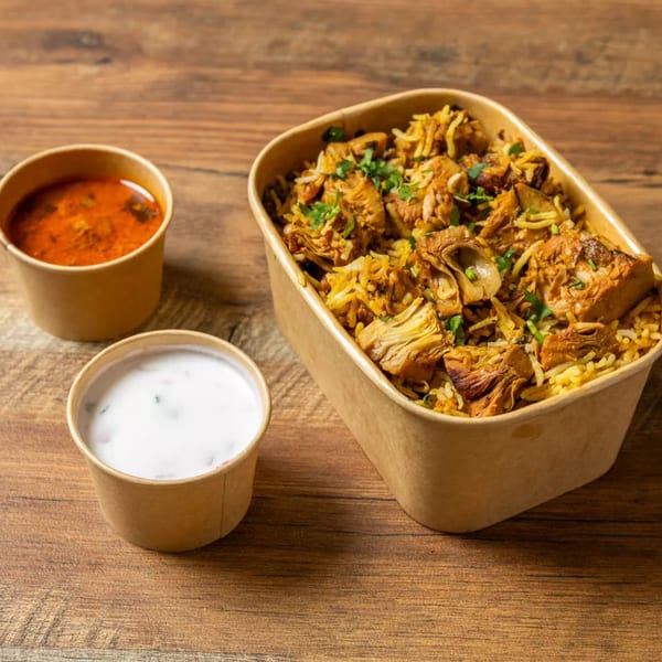 Jackfruit biryani in a takeaway container, with a side of red curry and white raita.